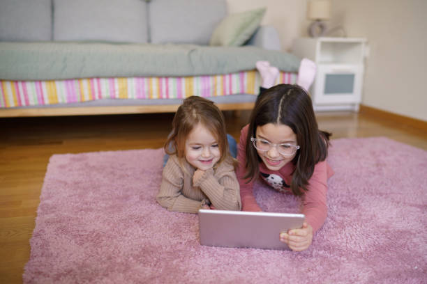 istock Cute girls using digital tablet at home 2203640837
