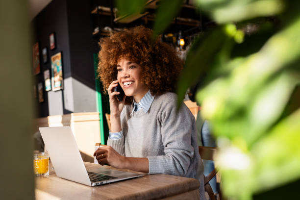 istock Charming Woman Enjoying Coffee and Laptop Time at Coffee Shop While Using Phone 2203643075