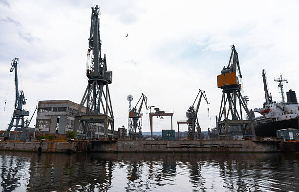 A busy industrial shipyard with large cranes, dockside buildings, and a ship, reflecting maritime trade importance and construction facilities. Varna, Bulgaria