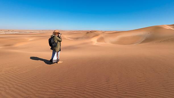 istock Photographer on sand dunes under blue sky 2203651250