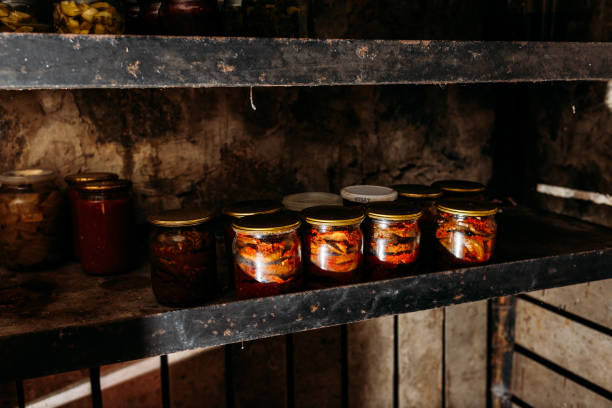 Home canning in glass jars in the cellar, canned tomatoes, cucumbers, eggplants, processing vegetables. Jars with Home Canning Fruits and Vegetables. Shelves of homemade preserves and canned goods