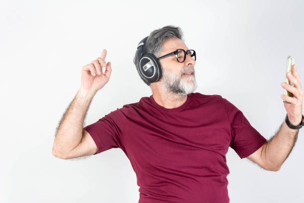Perfect song. Perfect song. Part of portrait of handsome mature man listening to music in headphones with smile while standing against white background gay man men sunglasses party stock pictures, royalty-free photos & images