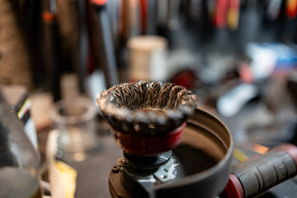 A detailed view of a wire brush tool on a workbench, surrounded by a busy workshop background, conveying craftsmanship and industrial activity.
