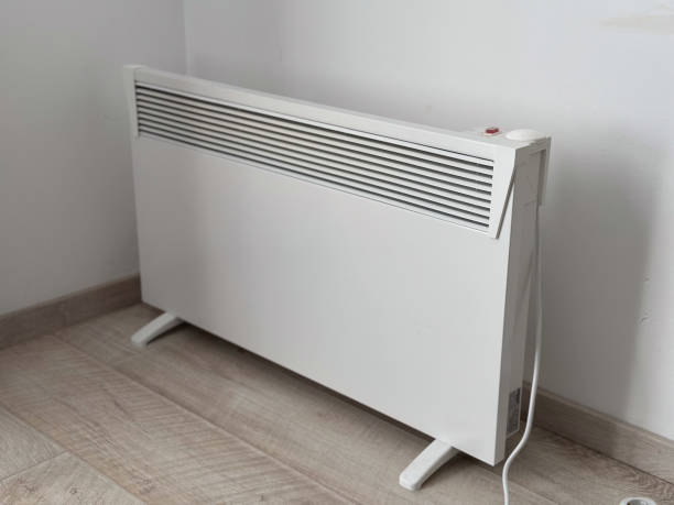istock Modern white electric heater placed against a plain wall. Functional design and a minimalist approach to home heating solutions. heating cost problem 2203658390