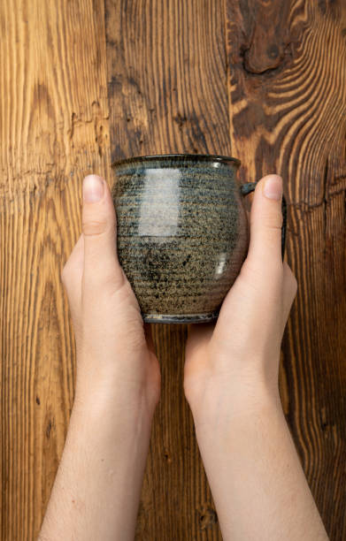 istock Hand Holds Cup, Empty Cup in Hands, Coffee Mug, Teacup Mockup, Cup in Arms on Wooden Table 2203665815