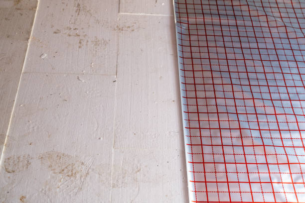 Installing red grid vapor barrier film on insulated floor
