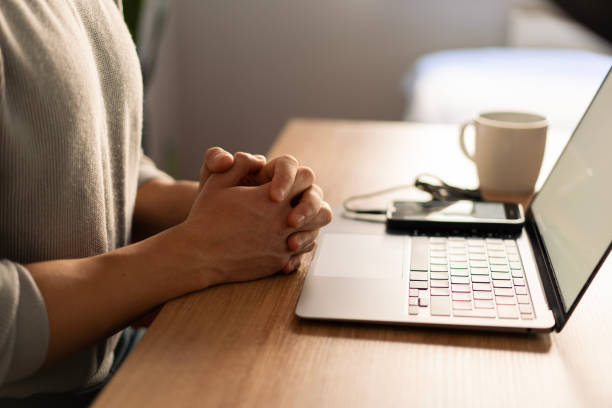 istock Businesswoman clasping hands while working remotely at home office desk 2203668041