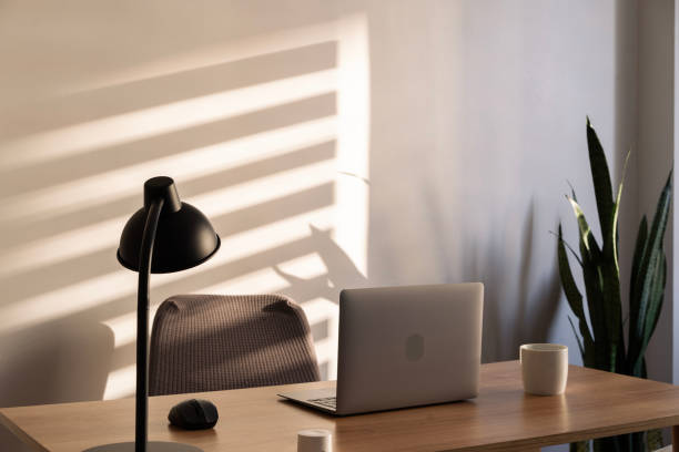 istock Modern home office setup basking in warm sunlight with laptop and lamp 2203668046