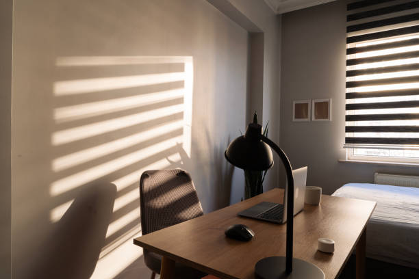 istock Sun shining through blinds into cozy home office 2203668127