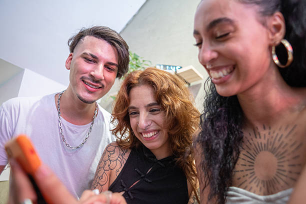 A group of smiling friends watching something interesting on a smartphone.