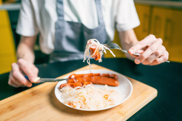 A pair of delicious Viennese sausages with Kaisersemmel, mustard and horseradish on a white paper plate. A blue patterned cloth napkin serves as the base.