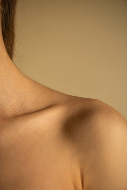 istock Part of a woman's shoulder on a beige background 2203674252