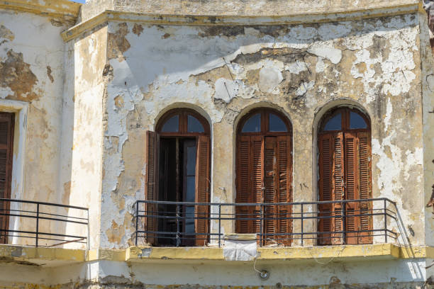 Abandoned old villa fronting street with deteriorated exterior peeling paint,weathered facade at Kos Greece.