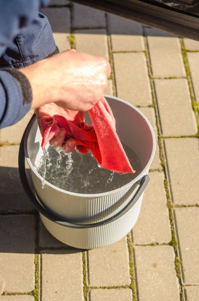 Man Squeeze Water from hands and washing wipe into Bucket Outdoors on Sunny Day. High quality photo