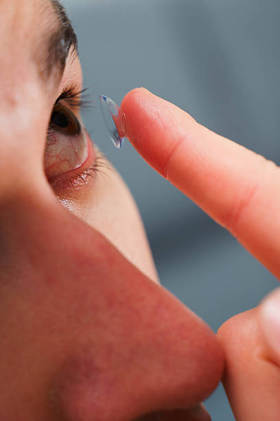 istock Correcting eye wellnesses with optical contact lenses. Man inserts a contact lens into eye for myopia treatment. 2203688918