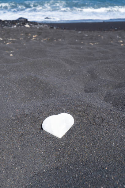 meditating on wild beach shore, crystal heart with flower of life pattern
