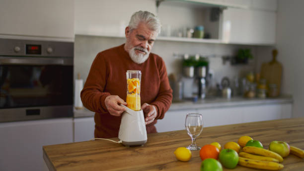 istock Old retired man making fruit and vegetable shake at home 2203692060