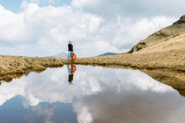 istock Solo Hiker Crossing a Reflective Mountain Stream 2203693594
