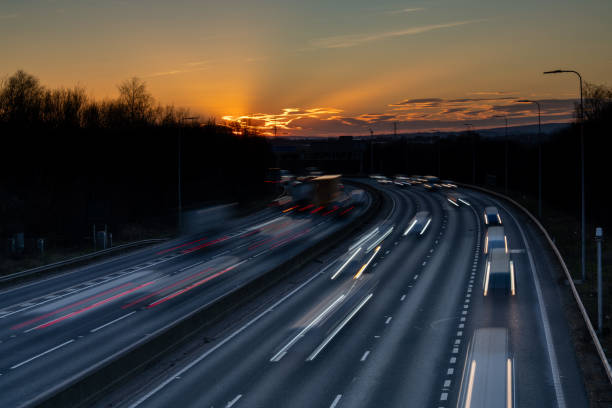 istock Cars driving on highway at sunset creating light trails 2203696543