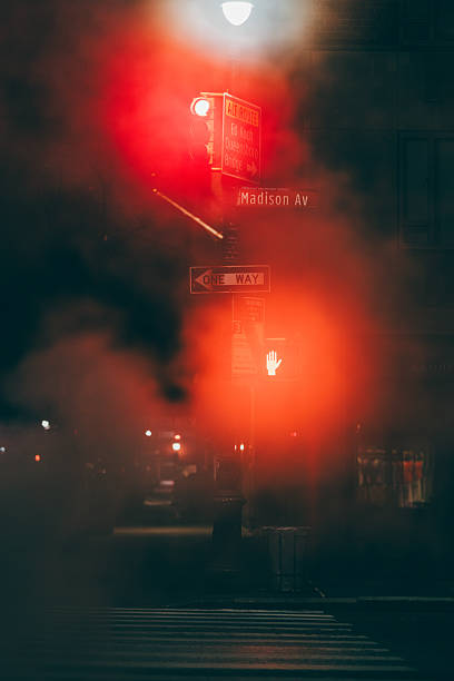 A street sign with a red light on it. The sign is on a pole