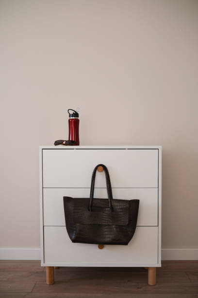 istock A minimalist white nightstand with a bag and coffee thermos, perfect for any setting 2203699804