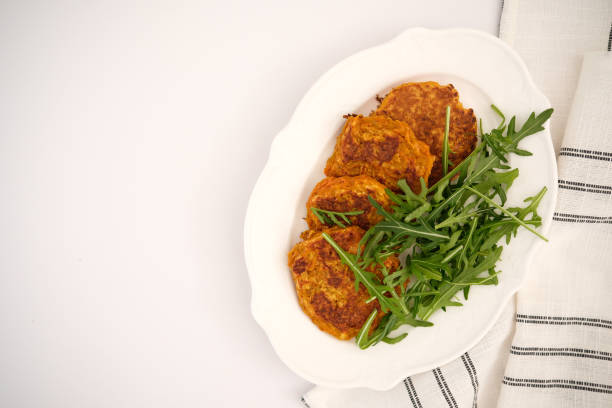 istock Carrot pancakes with rucola on white plate with napkin. 2203701943