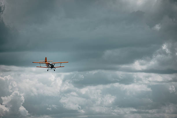 istock Small yellow plane flying in blue white blue cloudy sky. Private cessna plane in clouds. 2203703780