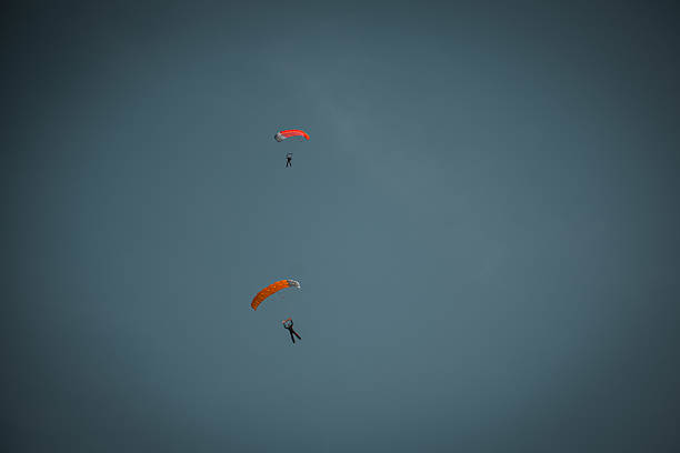 istock Paragliding flight in dramatic cloudy sky. Hang gliders silhouette with parachute against white and dark clouds 2203703786