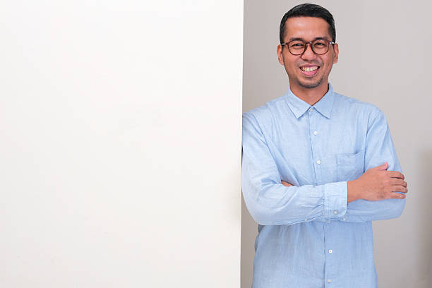 istock A man standing beside a wall with arms crossed and showing happy expression 2203704695
