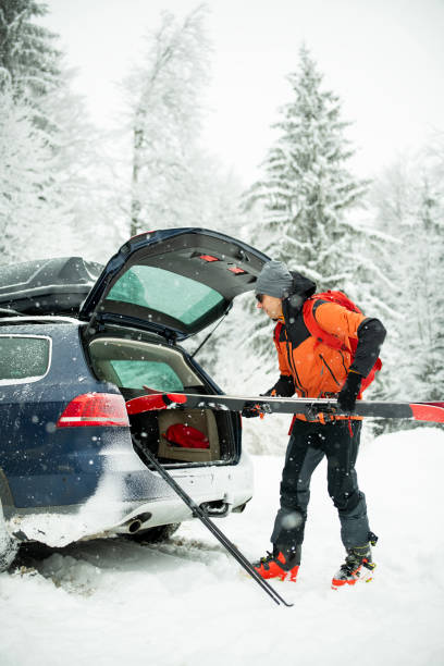 istock A man unpacking ski equipment from the tailgate of a car. 2203712167