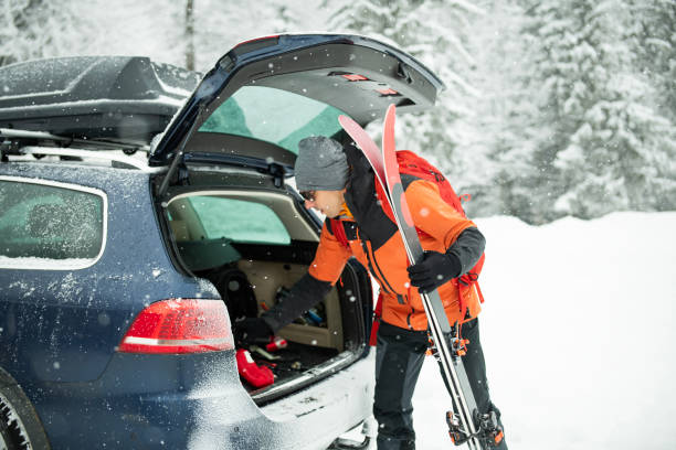 istock A man unpacking ski equipment from the tailgate of a car. 2203712170