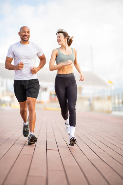 istock Two runners share a motivational run on a sunny boardwalk 2203712704