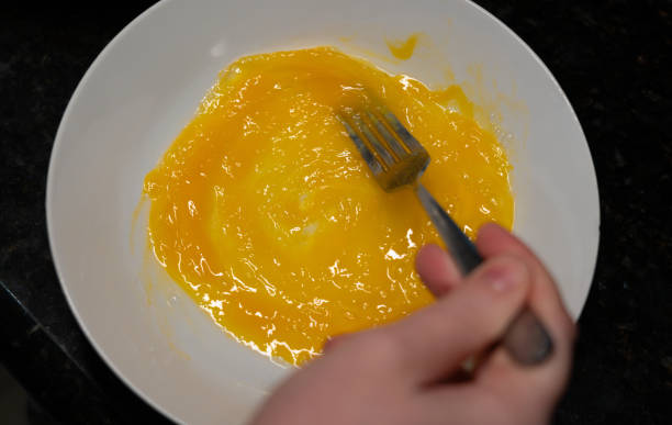 istock Female hands beat eggs with fork in a bowl, homemade schnitzel cooking process closeup 2203713248