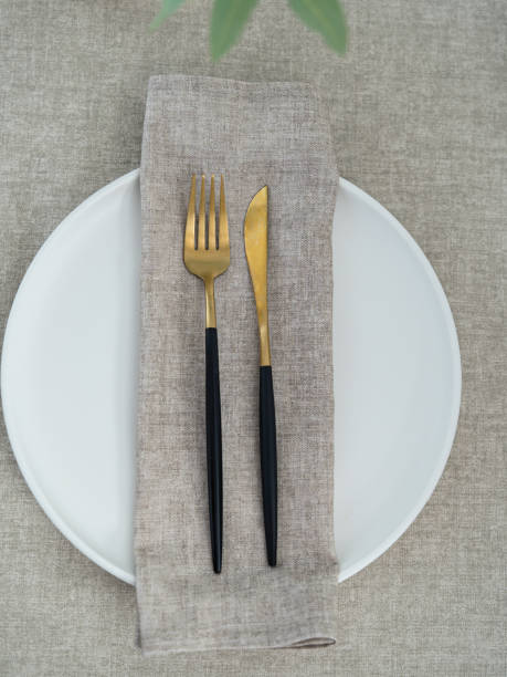 istock Beige napkin on a white plate. Table setting. Fork and a knife. 2203713661