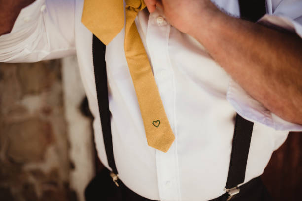 Groom tying his necktie with heart embroidered on the back