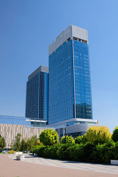 istock Modern skyscraper architecture showcases glass facade and nearby greenery under clear blue sky 2203733077