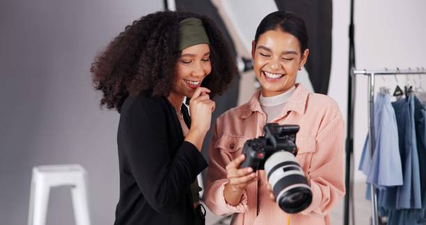 istock People, camera and discussion for photoshoot on set, collaboration and instructions for shooting. Women, photographer and speaking to stylist for fashion feedback, review image and laughing backstage 2203733717