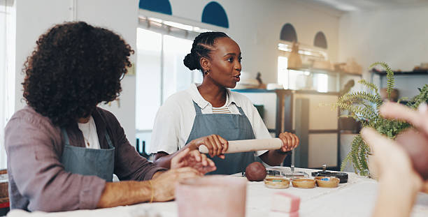 istock Woman, pottery workshop and teaching people in class, artistic crafts and rolling pin for molding. Shape, clay sculpture and ceramic learning with instructor, training students and group for lesson 2203735361
