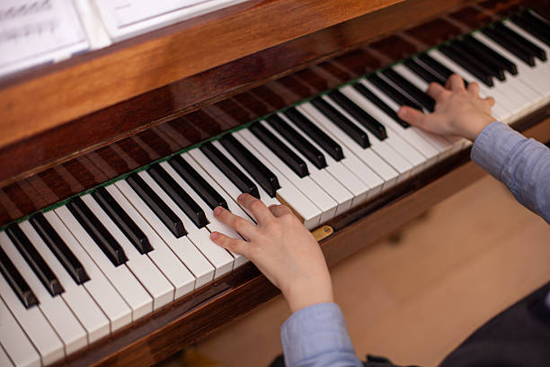 istock Child's hands playing piano. Boy has piano lesson. 2203737943
