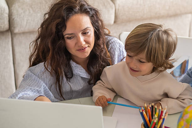 istock Mother guiding her young son through homework tasks, utilizing a laptop for online learning and educational resources in the comfort of their home, fostering connection and growth 2203739005