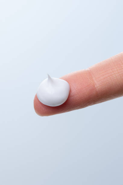 istock Woman's finger with cosmetic white cream 2203739136