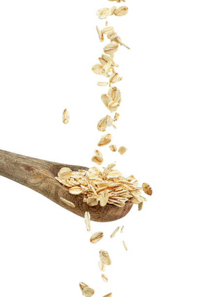 istock Oat flakes falling into spoon on white background, levitation 2203739394