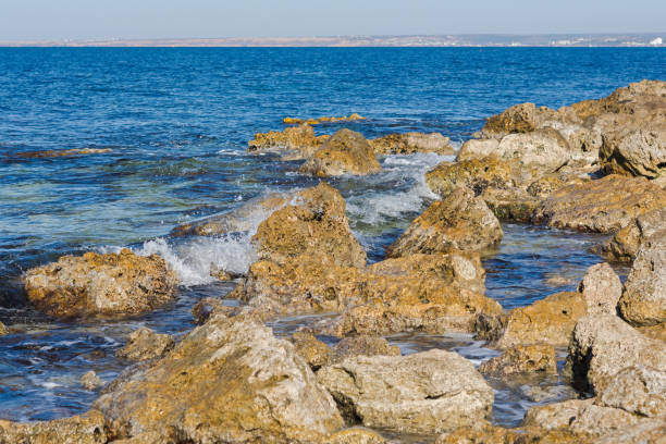Sea of stones close-up. Bright blue sea and brown reefs. Authentic marine design background. The concept of vacation, relaxation and enjoyment. Blue waves are rolling on beach. The Black Sea coast