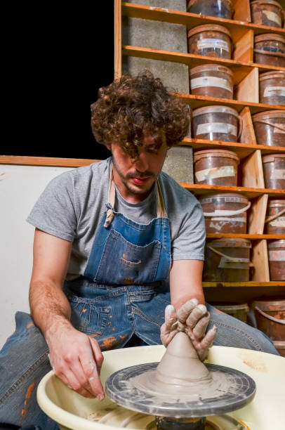 istock Potter creating clay vessel on pottery wheel in workshop 2203741324