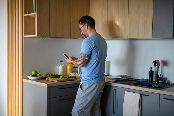 istock Diabetic man with CGM sensor checking his blood sugar level while making healthy breakfast. 2203741702
