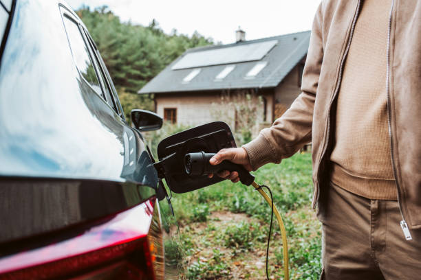 istock Man charging electric car, plugging charger in charging port. 2203742343