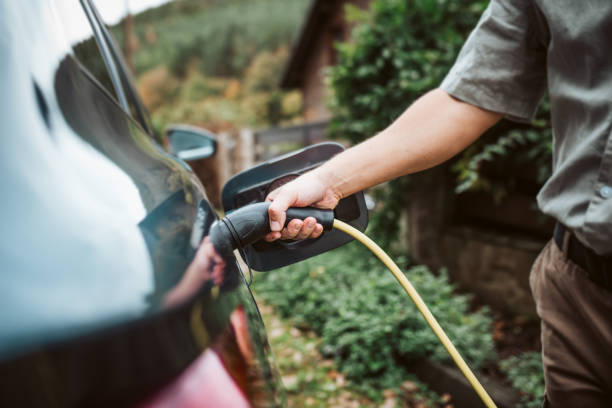 istock Man charging electric car, plugging charger in charging port. 2203742384