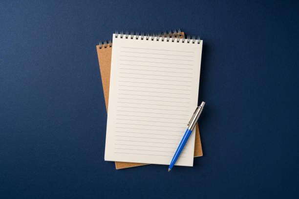 istock Top view of notebook and ballpoint pen on blue background 2203743969