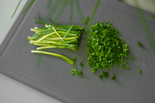 Chopped green onions lie on a grey board.