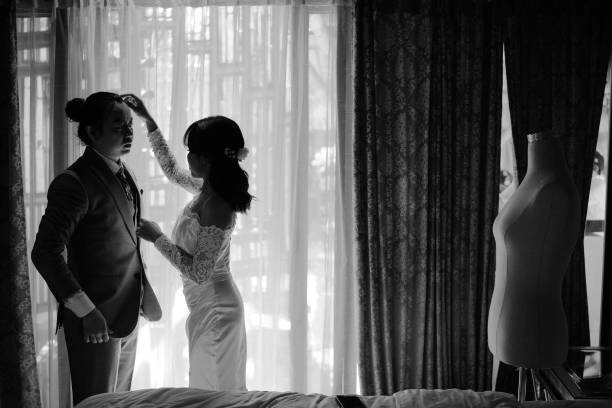 istock Asian Bride Fixes Groom’s Tied-Up Long Hair in Soft Light 2203746770